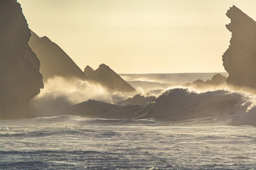 Obraz na płótnie Canvas Waves crashing on Portugal coastline at sunset