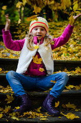 little kid throwing leaves in colorful park in fall season