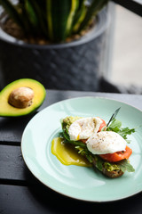 Hot toast with salmon, poached egg, herbs and avocado on a plate with a black copy space flag on a skewer