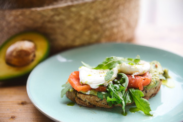 Hot toast with salmon, poached egg, herbs and avocado on a plate with a black copy space flag on a skewer