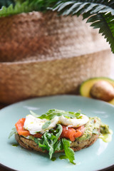 Hot toast with salmon, poached egg, herbs and avocado on a plate with a black copy space flag on a skewer
