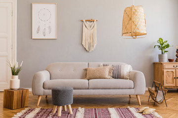 Stylish and design home interior of living room with gray sofa, wooden cube, commode, pillow, macrame, rattan lamp, basket, plants and elegant accessories. Stylish home decor. Template. Mock up poster