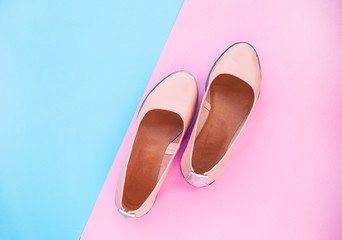 Beautiful minimalistic pink color female shoes on dark blue and pastel pink background with copyspace.