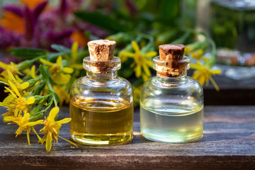 Obraz na płótnie Canvas Bottles of essential oil with European goldenrod twigs