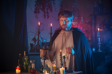 portrait of  wizard with burning candles and magic potions