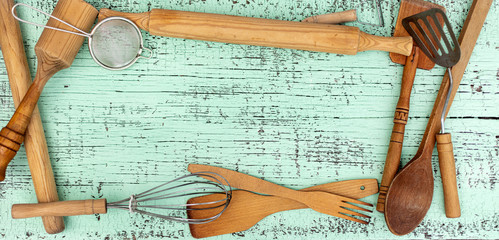 Vintage old kitchen utensils on a green wooden background.