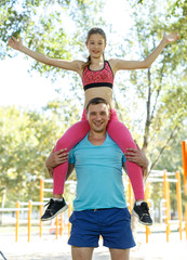 Athletic man holding on shoulders his daughter