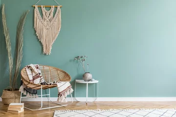 Fotobehang Boho Stylish minimalistic interior of living room with design rattan armchair, palm leaf in basket, plaid, beige macrame on the wall, flowers and elegant accessories. Eucalyptus color of wall. Copy space.   © FollowTheFlow