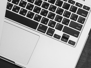 Macbook laptop keyboard with Russian-English layout on a black wooden background