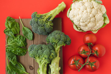 Vegetables Close Up Top View. Fresh Organic Tomatoes, Spinach, Cauliflower and Broccoli Close Up on Red Background. Group of Objects, Healthy Eating, Healthy Lifestyle, Product