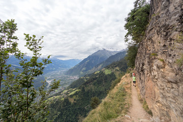 Wanderweg in den Alpen mit Frau und Mann mit Blick ins Tal