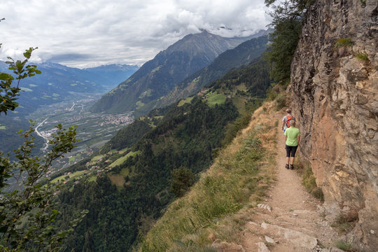 Wanderweg in den Alpen mit Frau und Mann mit Blick ins Tal