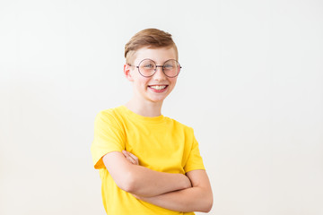 Handsome laughing teen boy on white background. Smiling young man stands with folded hands