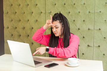 Loser! Portrait of unhappy rude young girl freelancer with black dreadlocks hairstyle in pink...