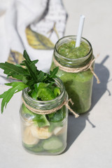 Vegetable smoothies and sliced ingredients cucumber, banana, paprika in two jars