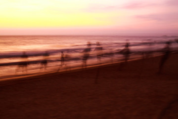 Long time exposure: Ghostly silhouettes of blurred fishermen catch up their net during sunset on...