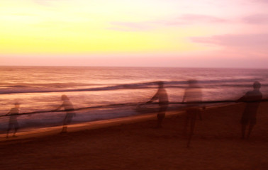 Long time exposure: Ghostly silhouettes of blurred fishermen catch up their net during sunset on...