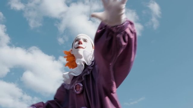 Cosplay or Halloween celebration. Street performer with make-up and in a suit as IT is dancing against the sky with clouds. Dancing clown in the image of a pennywise.