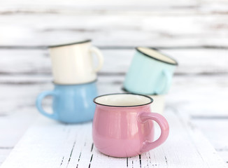 Enameled mugs in retro style on an old wooden background.
