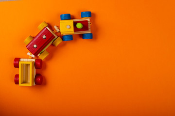 Wooden train on orange background with space for text.