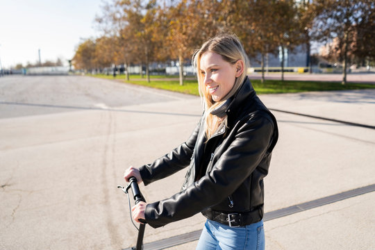 Smiling young woman with kick scooter