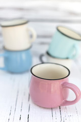 Enameled mugs in retro style on an old wooden background.