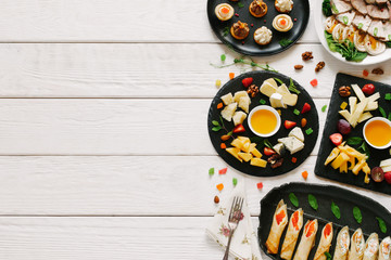 Luxury catering. Flat lay of plates with cheese and meat assortment appetizers served on white wooden table. Copy space.