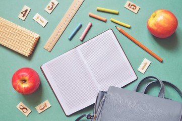 World Teachers' Day greeting card. Flat lay photo red apples, waffles, ruler, wooden cards with numbers, crayons and a backpack on a green table. Back to school concept