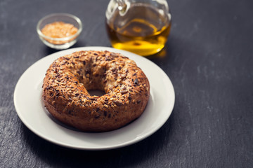 fresh bagel with seeds on white plate on ceramic background