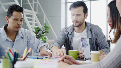 Group of casually dressed business people discussing ideas in the office. Creative professionals gathered at the meeting table for discuss the important issues of the new successful startup project.