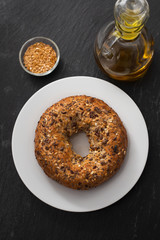 fresh bagel with seeds on white plate on ceramic background