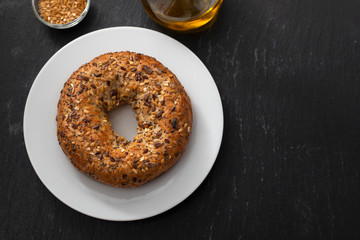 fresh bagel with seeds on white plate on ceramic background