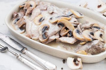 turkey with mushrooms and sauce on dish on ceramic background
