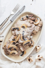 turkey with mushrooms and sauce on dish on ceramic background
