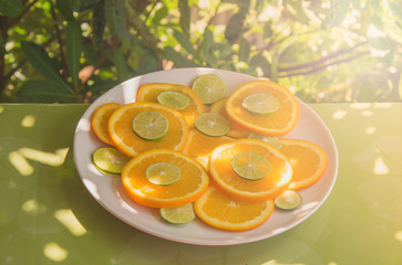 Close up shot of orange slices on white plate in soft sunlight. Healthy and vegetarian eating