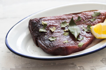 raw tuna with lemon and bay leaf on ceramic background