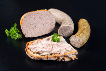 Traditionelle deutsche Streichwurst Pastete mit Bauernbrot angeboten als closeup auf schwarzen Hintergrund mit Textfreiraum