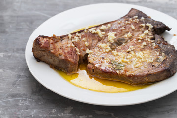 fried tuna with garlic, bay leaf and olive oil on white plate