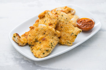 fried chicken breast with sauce on white dish on ceramic background