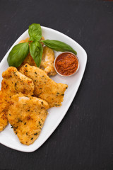 fried chicken breast with sauce on white dish on ceramic background