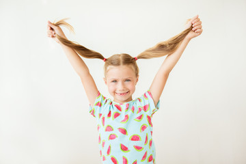 Portrait of beautiful smiling girl holding in her hands pigtails, closeup on white background