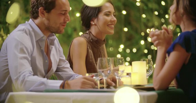 Four people, two couples happy talking and eating during a romantic gourmet dinner or lunch.Shiny lighting.Medium shot. Friends italian trip in Umbria.4k slow motion