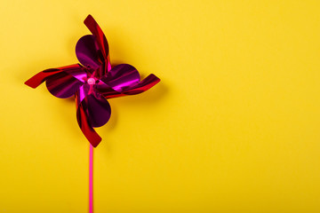 Pink Pinwheel on yellow background. Space for text on the right side of the image.