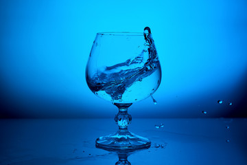 Water splash in glass on blue background