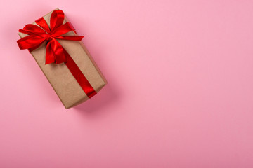 Gift box with bow on pink neon background. Space for text on the right side of the image.