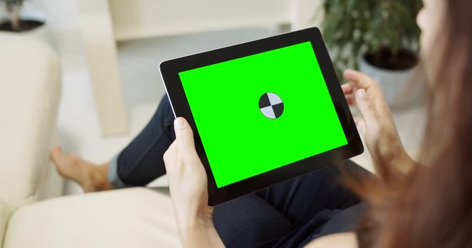 Lady in casual clothing sitting on couch and touching prekeyed tablet screen, gesture