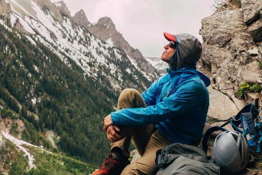 A man relaxes at the base of 'Guides Wall' on a stormy day, Cascade Canyon, Grand Teton National Park, Wyoming, USA