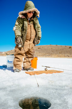 A man is fishing for trout on iced over Panguitch Lake, Dixie National Forest