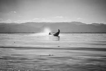Przewoźnik, rybak z Inle Lake płynący łodzią motorową przez jezioro - czarno białe.