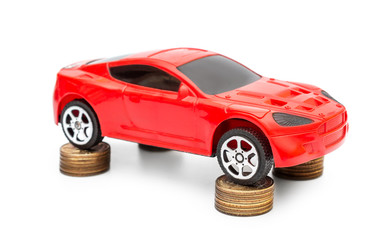 Red car toy with golden coins on white.